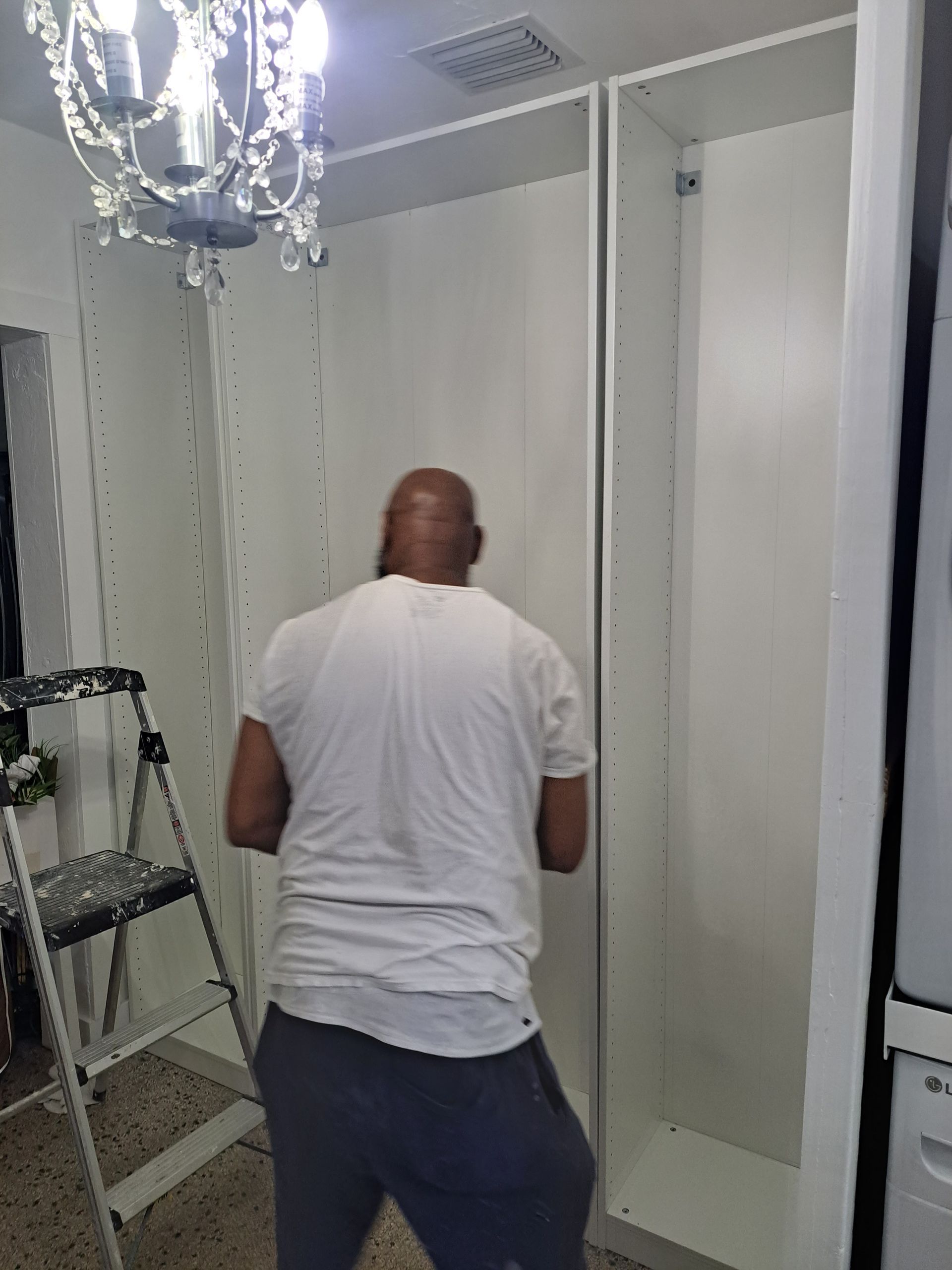 A man in a white shirt is standing in front of a white cabinet.