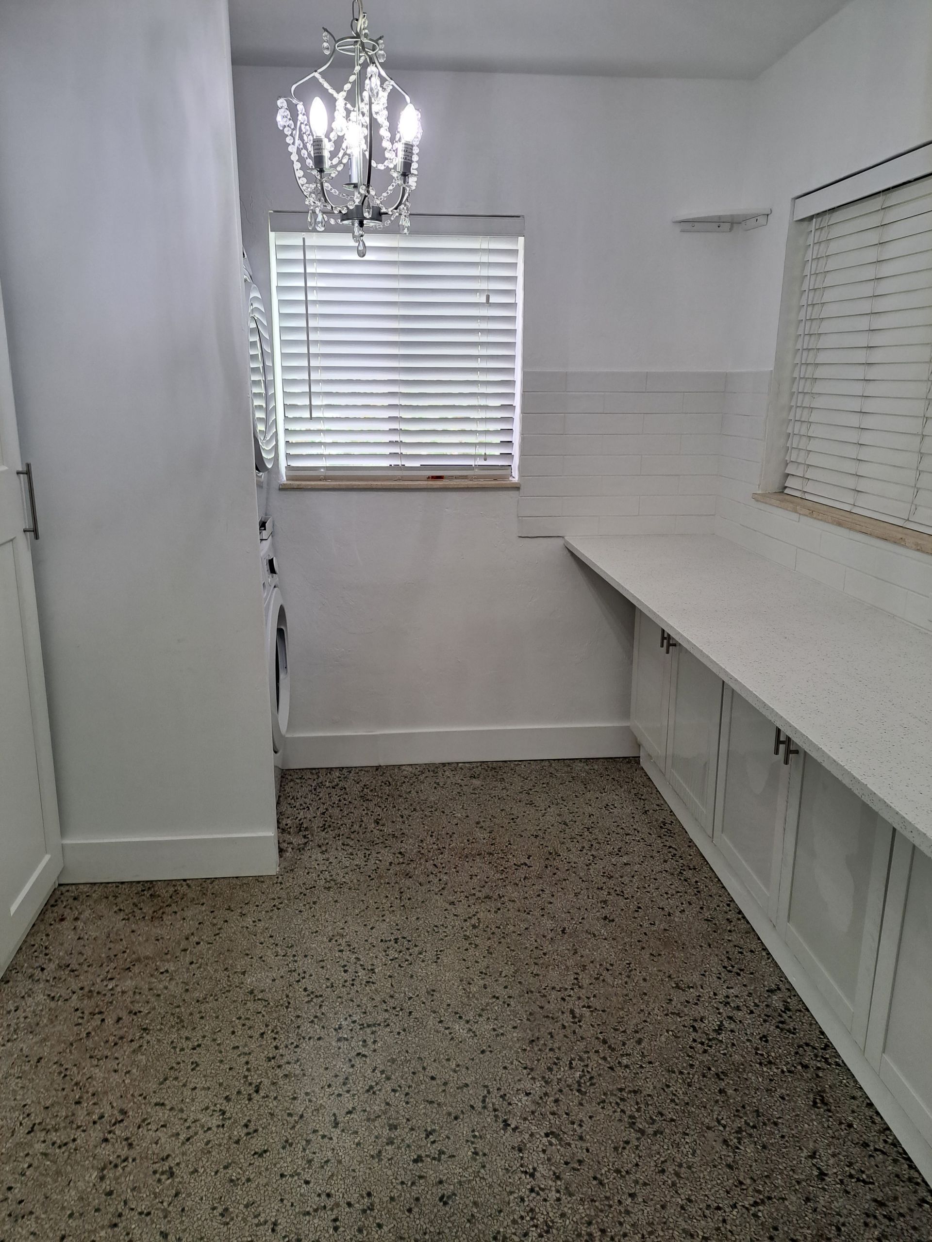 An empty kitchen with a chandelier and a window.