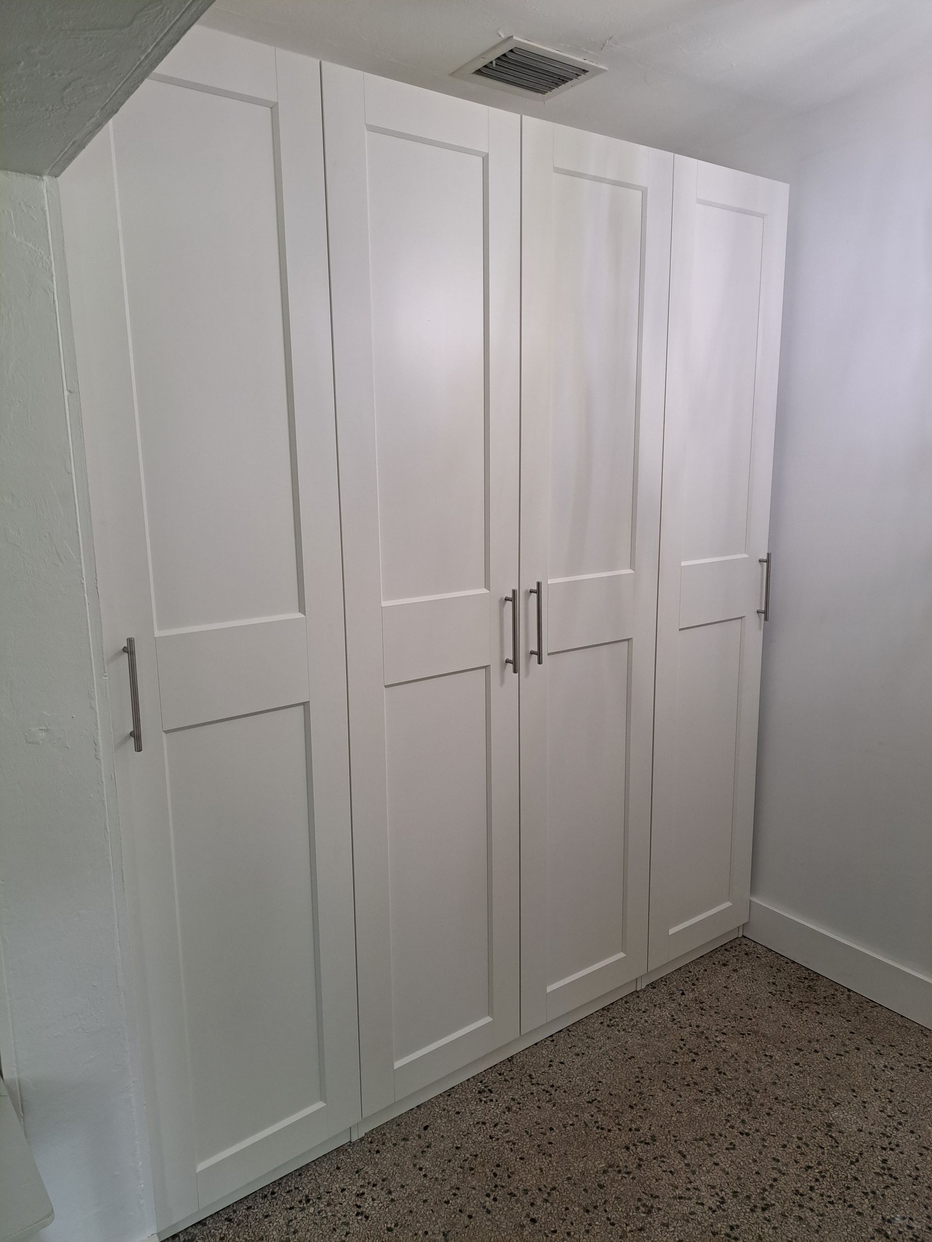 A room with a lot of white cabinets and a carpeted floor.