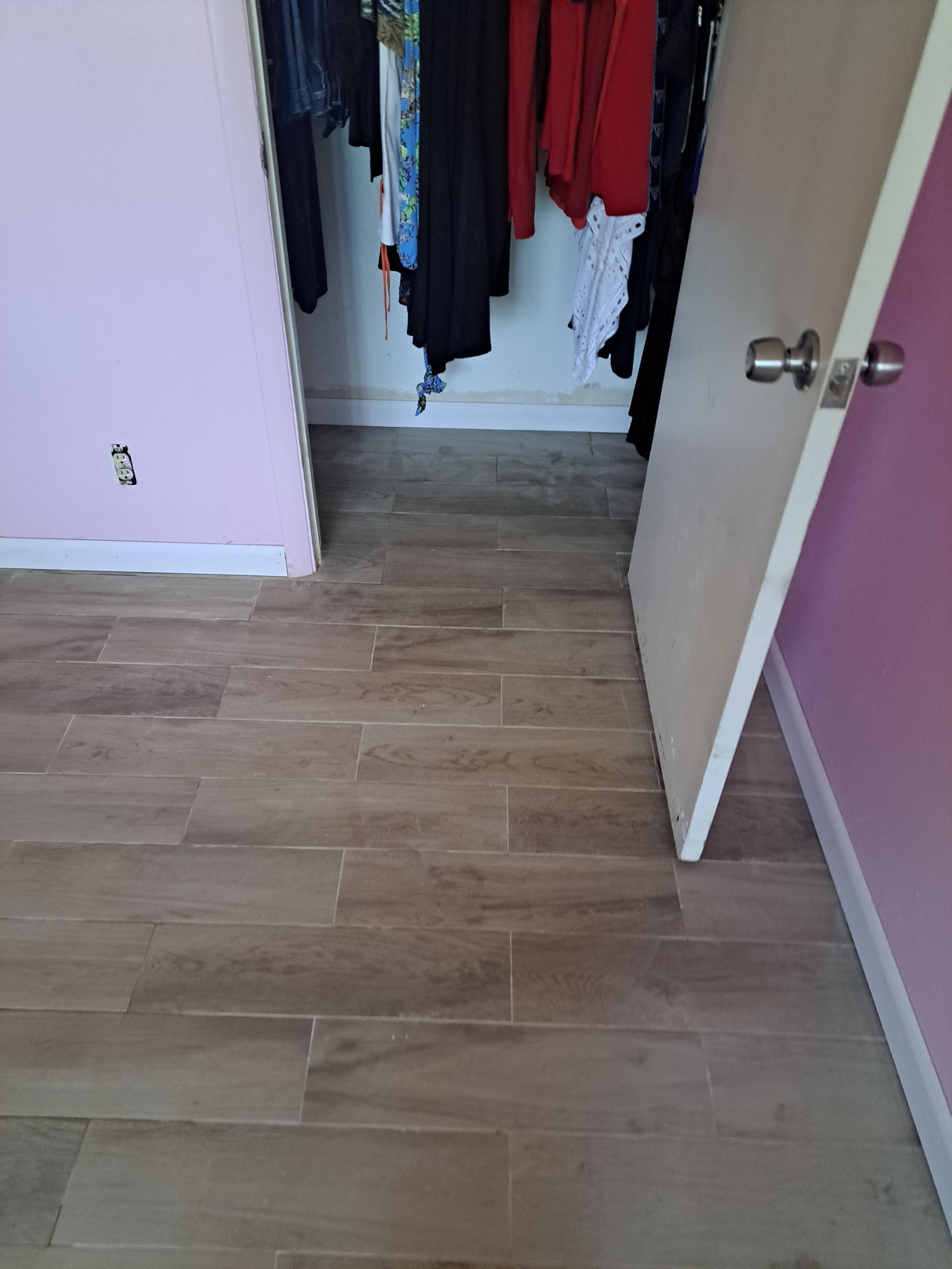 A closet with clothes hanging on the wall and a wooden floor.