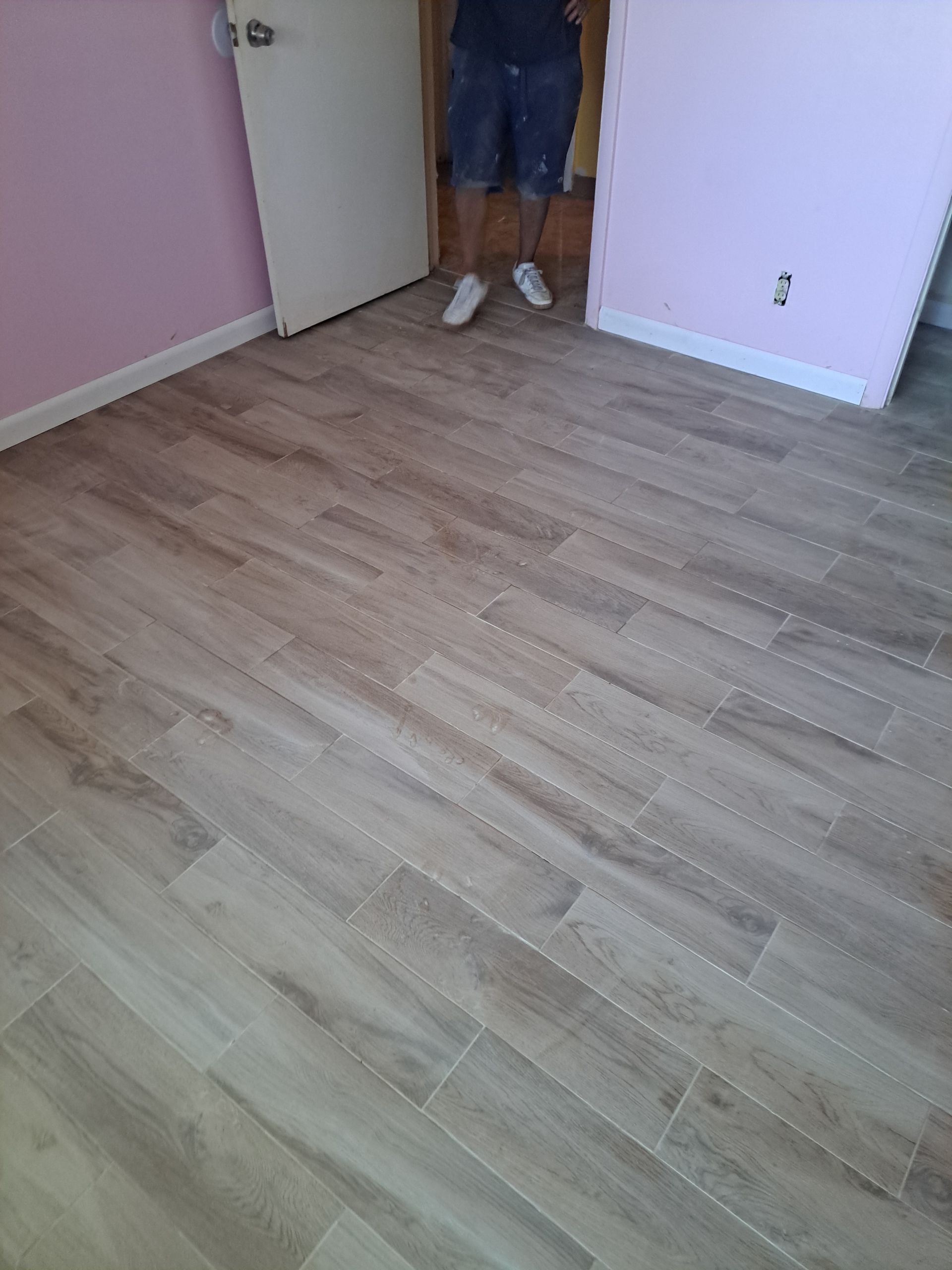 A man is standing on a wooden floor in a room.