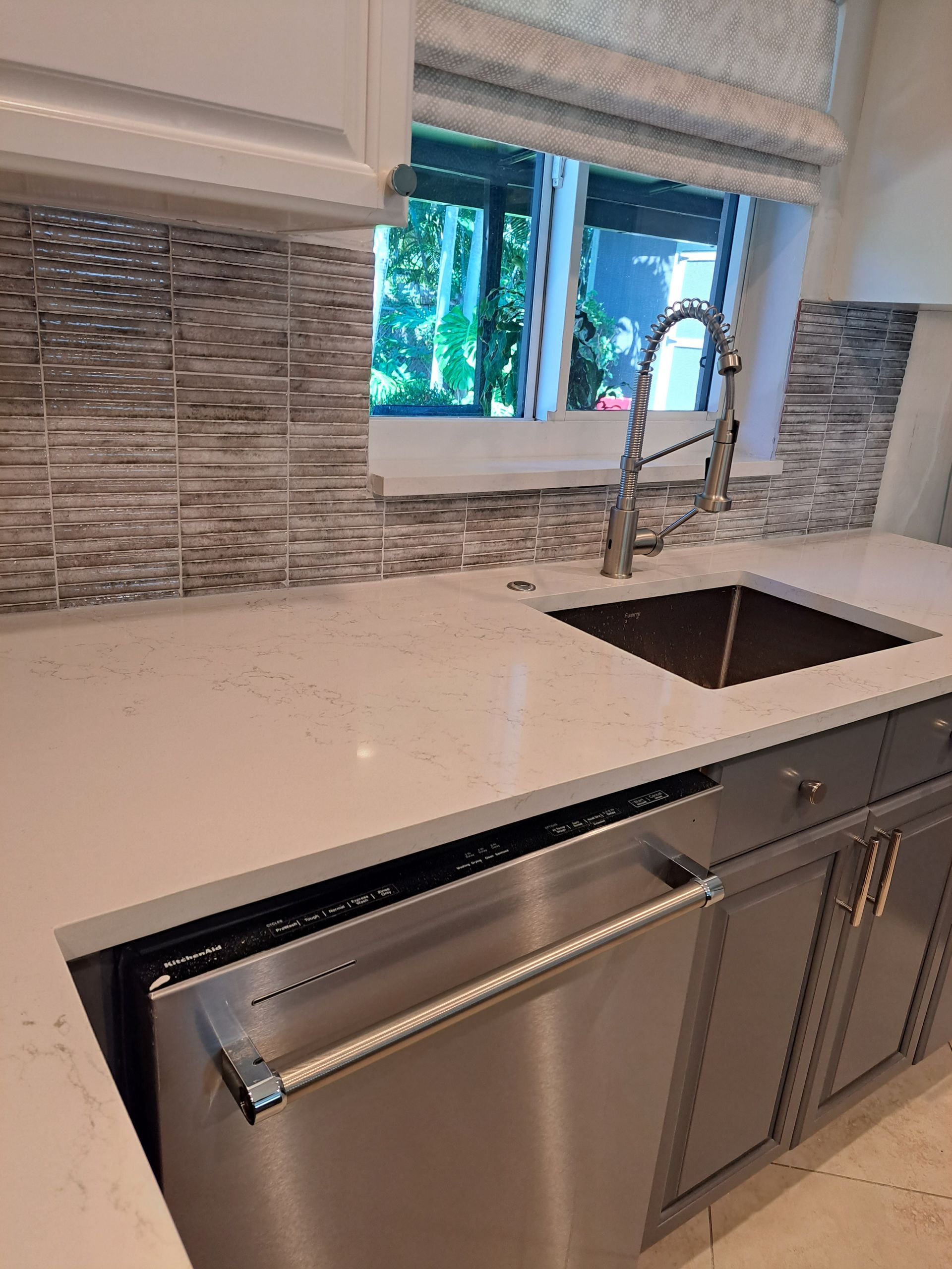 A kitchen with a sink , dishwasher , and window.