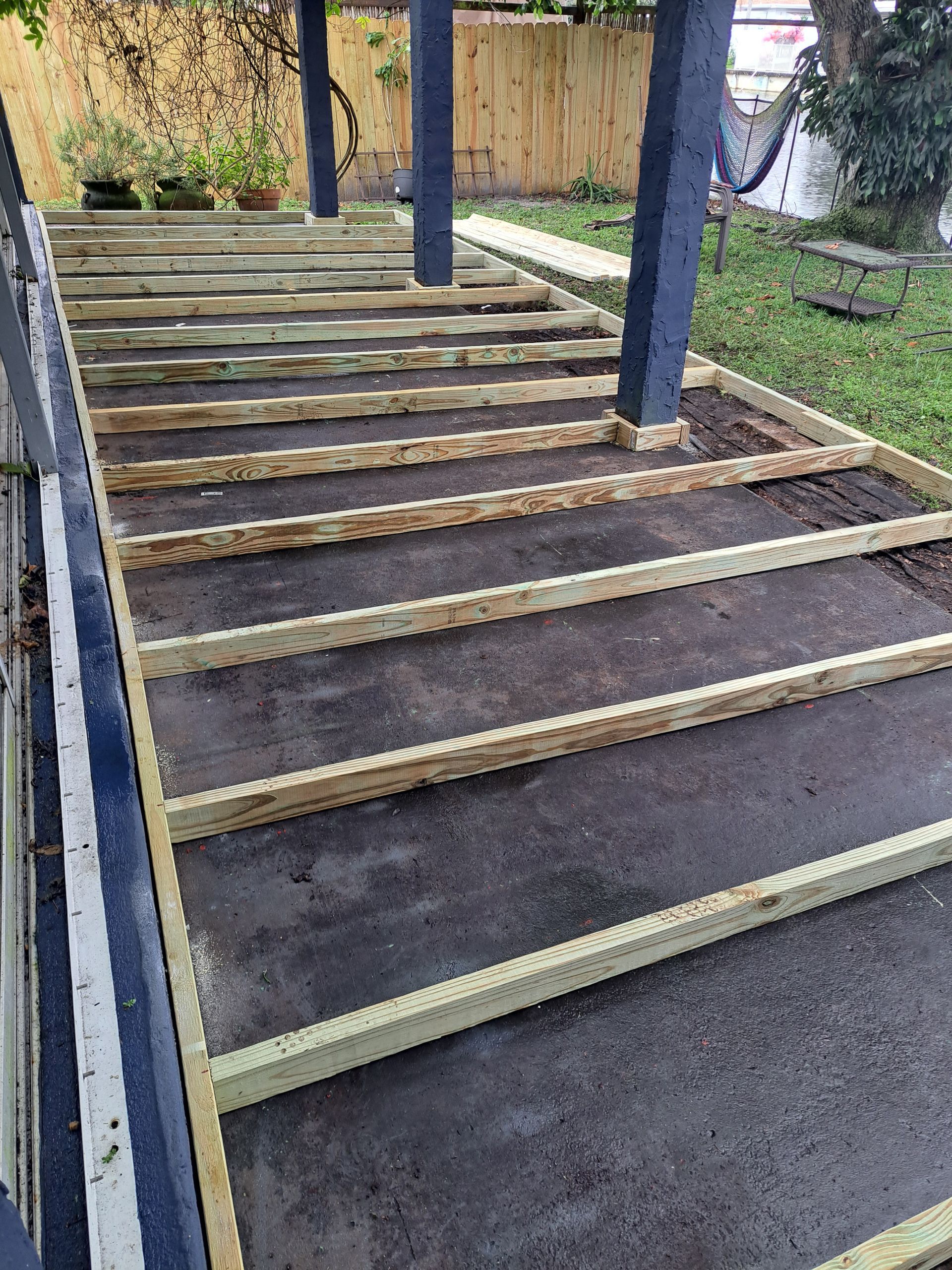 A wooden deck is being built in a backyard.