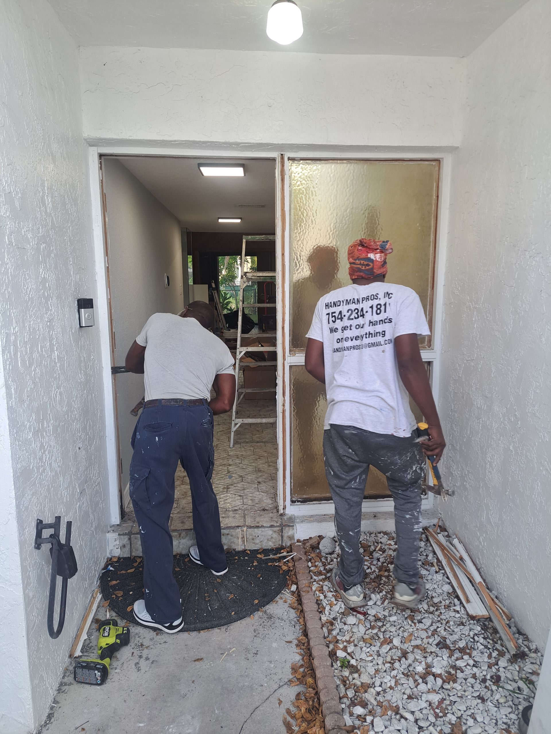 Two men are working on a sliding glass door.