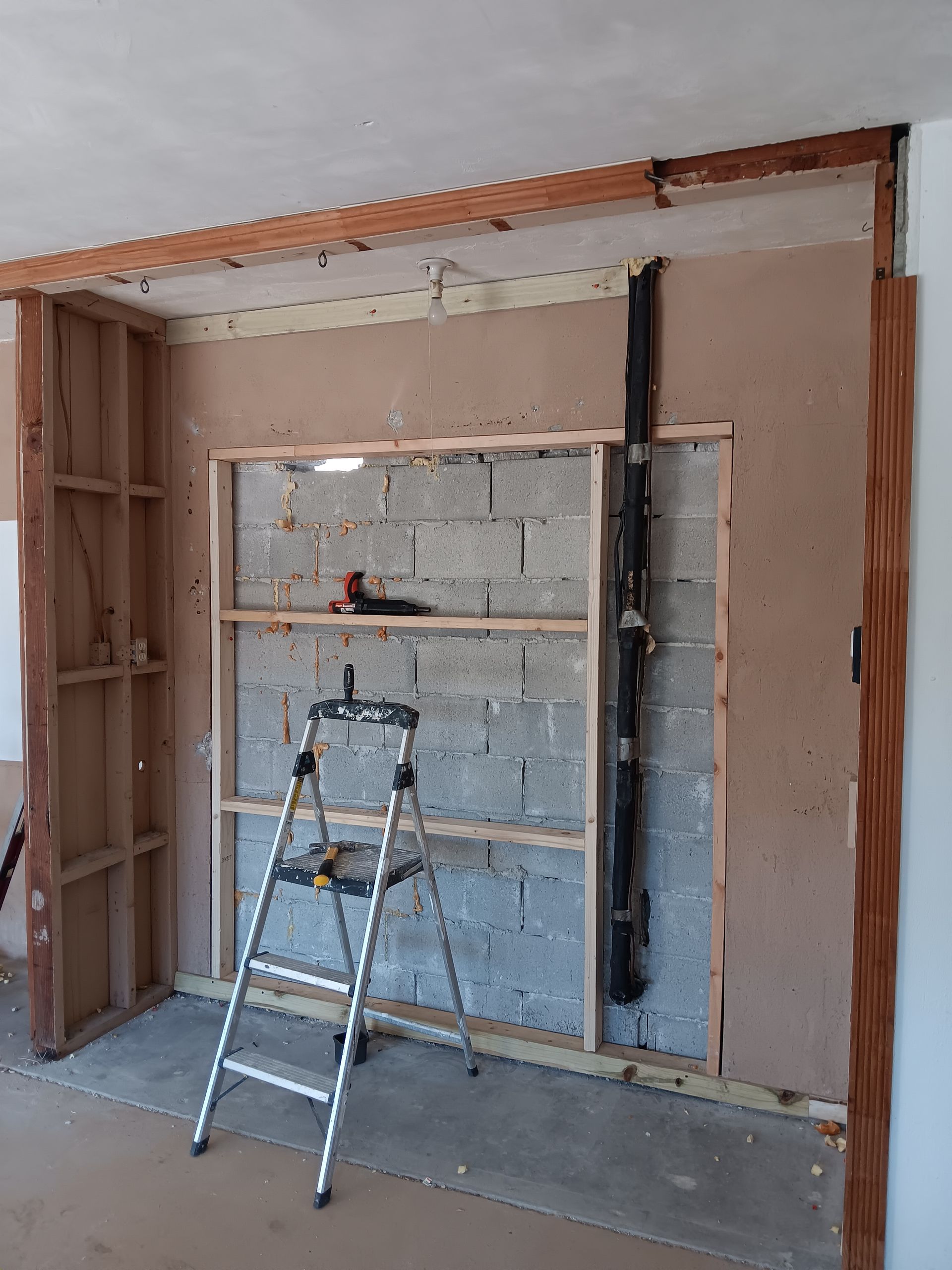A ladder is sitting in front of a brick wall in a room.