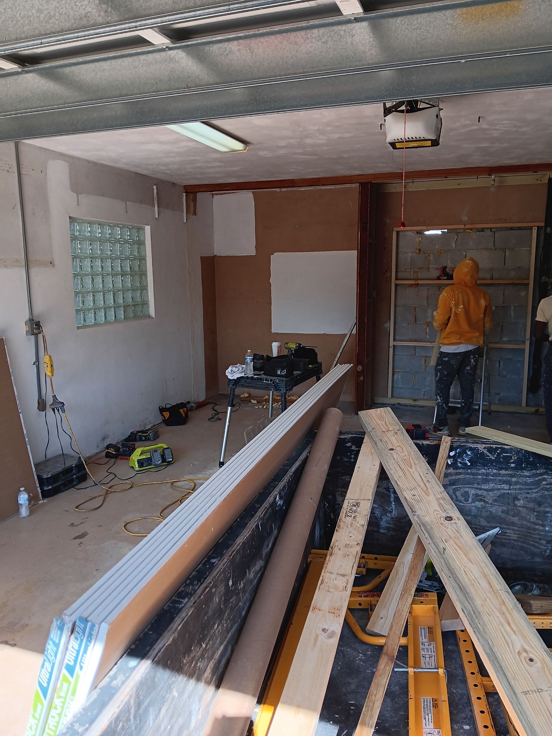 A man in a yellow hoodie is working in a garage