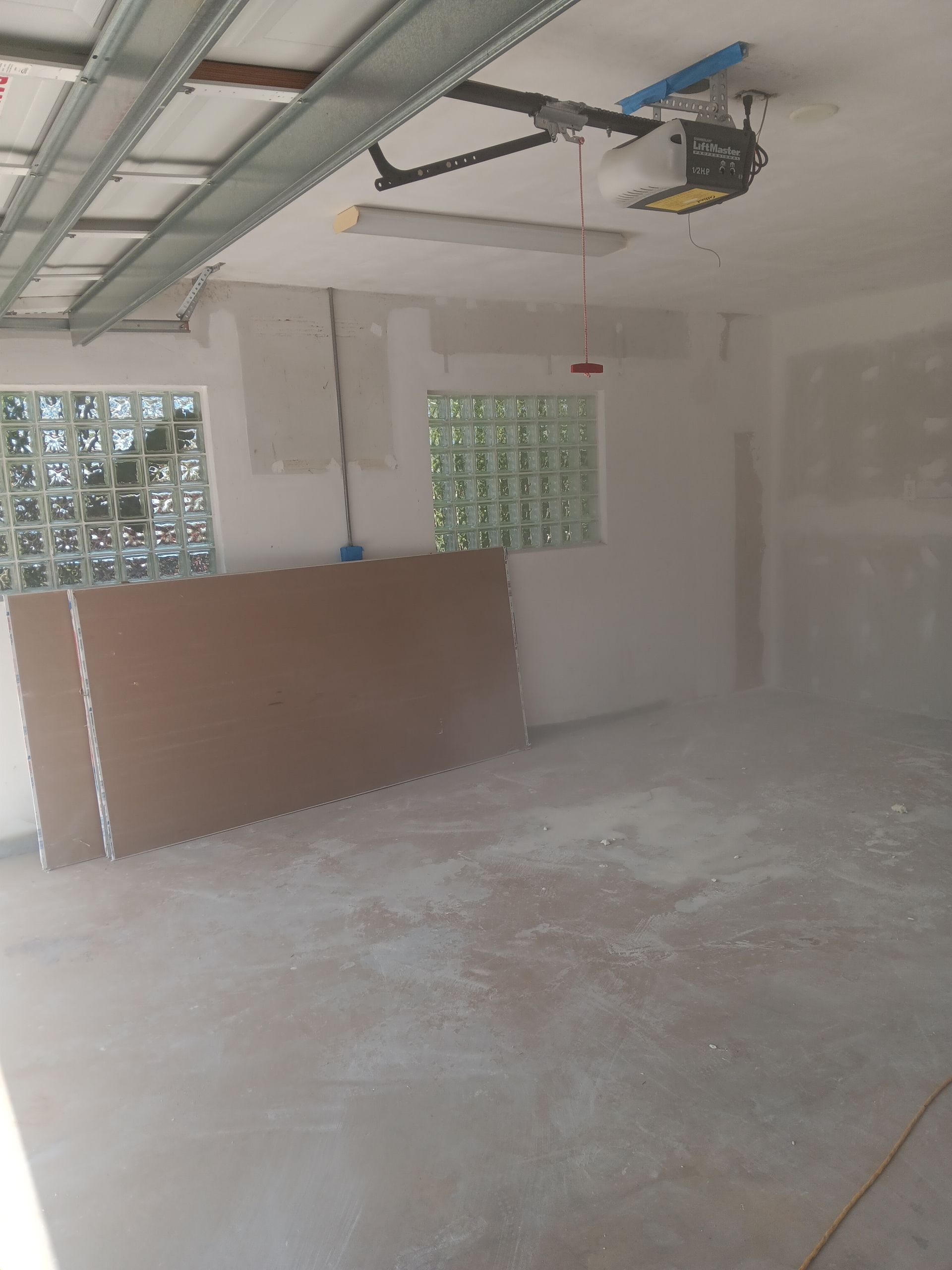 An empty garage with a garage door opener and a window.