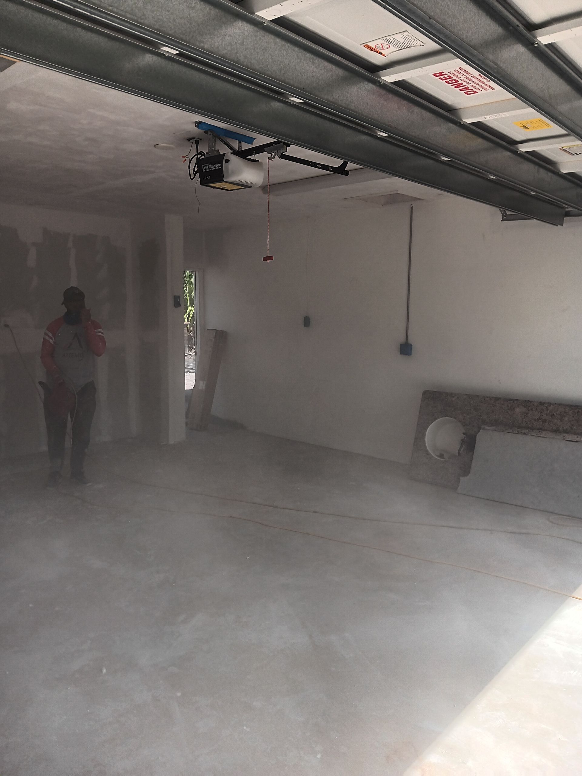A man is standing in an empty garage with smoke coming out of the ceiling.