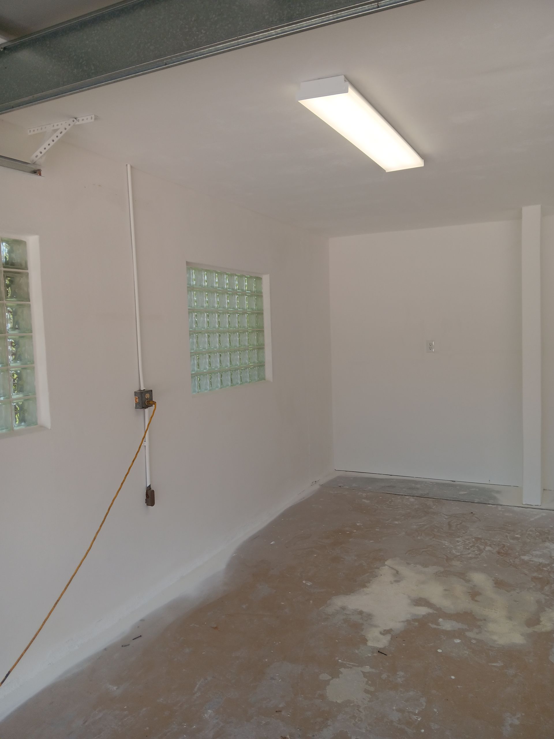 An empty garage with white walls and a light on the ceiling