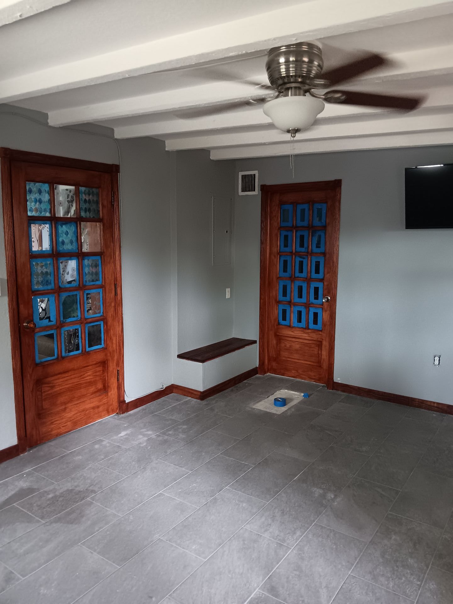 A room with a ceiling fan and wooden doors