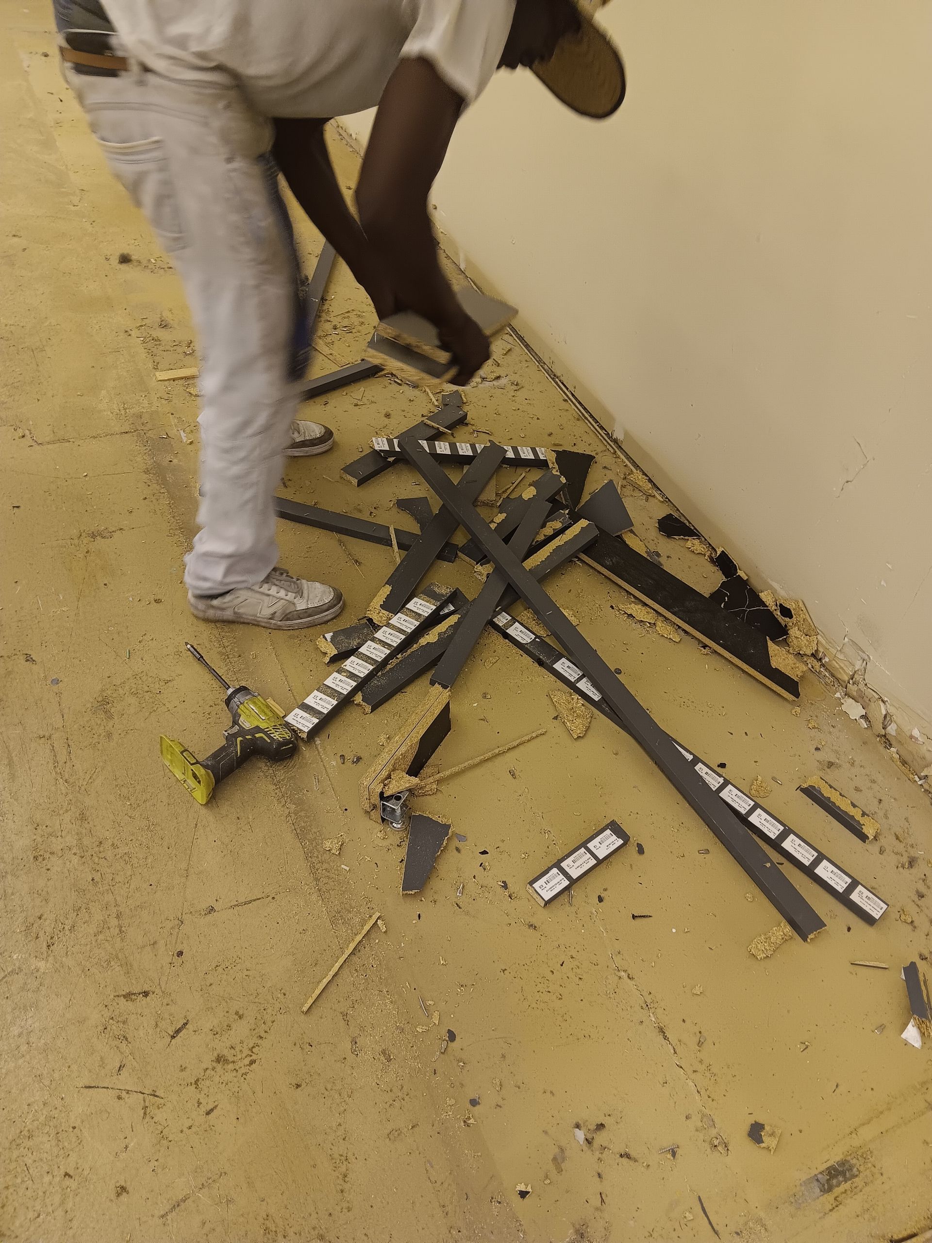 A person is working on a broken piece of equipment on the floor