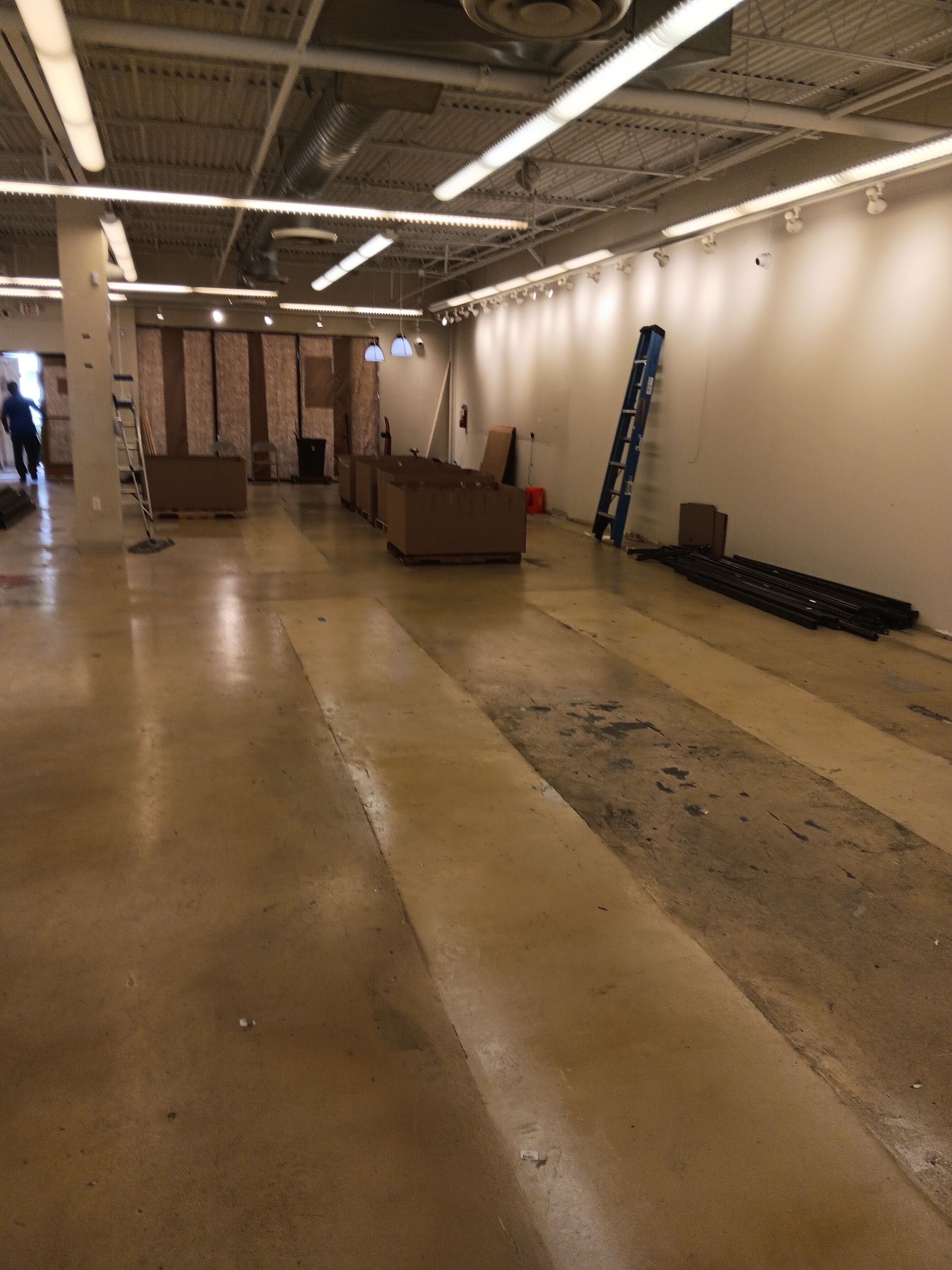 A large empty room with a ladder on the floor