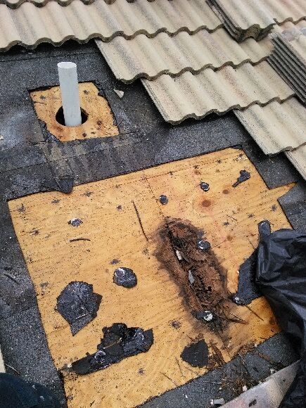 A roof with a hole in it and a pipe coming out of it.