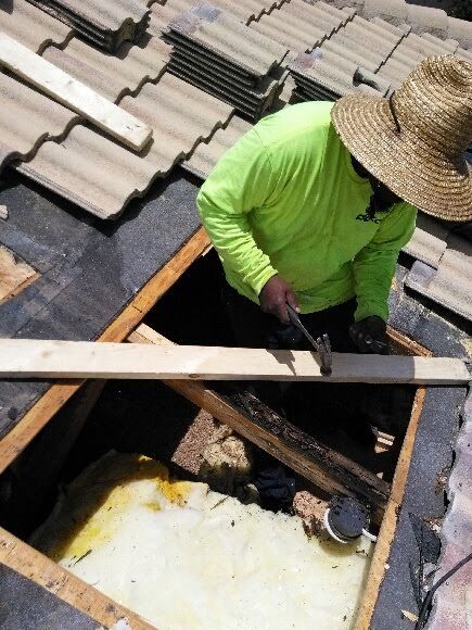 A man wearing a straw hat is working on a roof