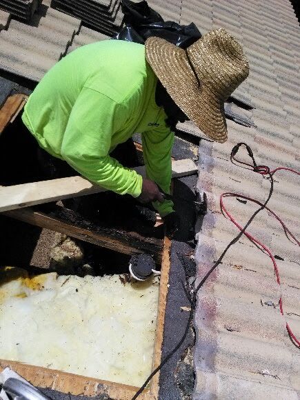 A man wearing a straw hat is working on a roof