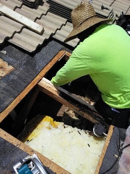 A man wearing a straw hat is working on a roof.