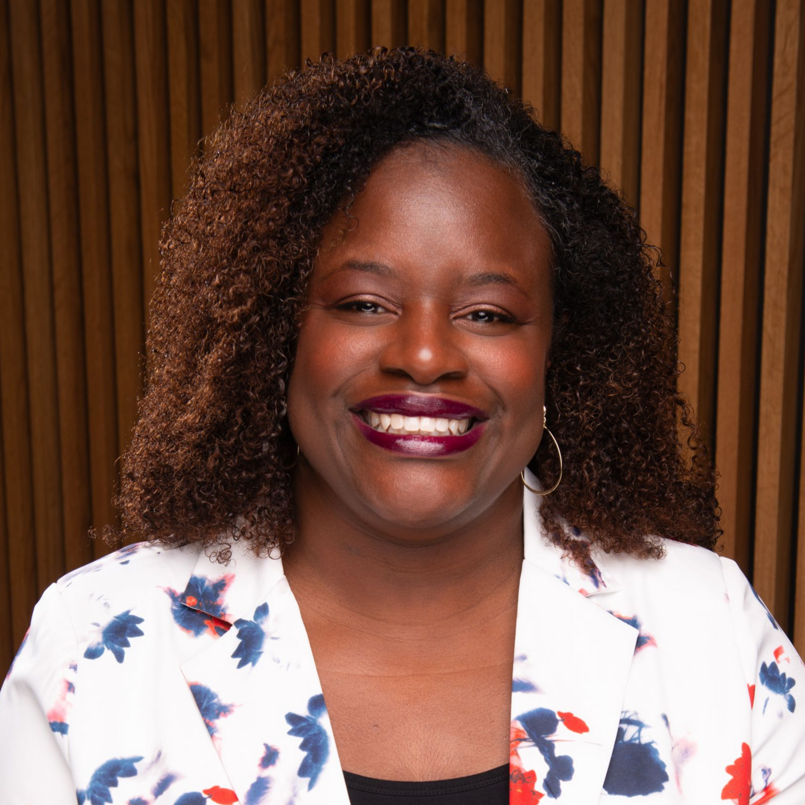 A woman with braids is smiling and wearing a white shirt