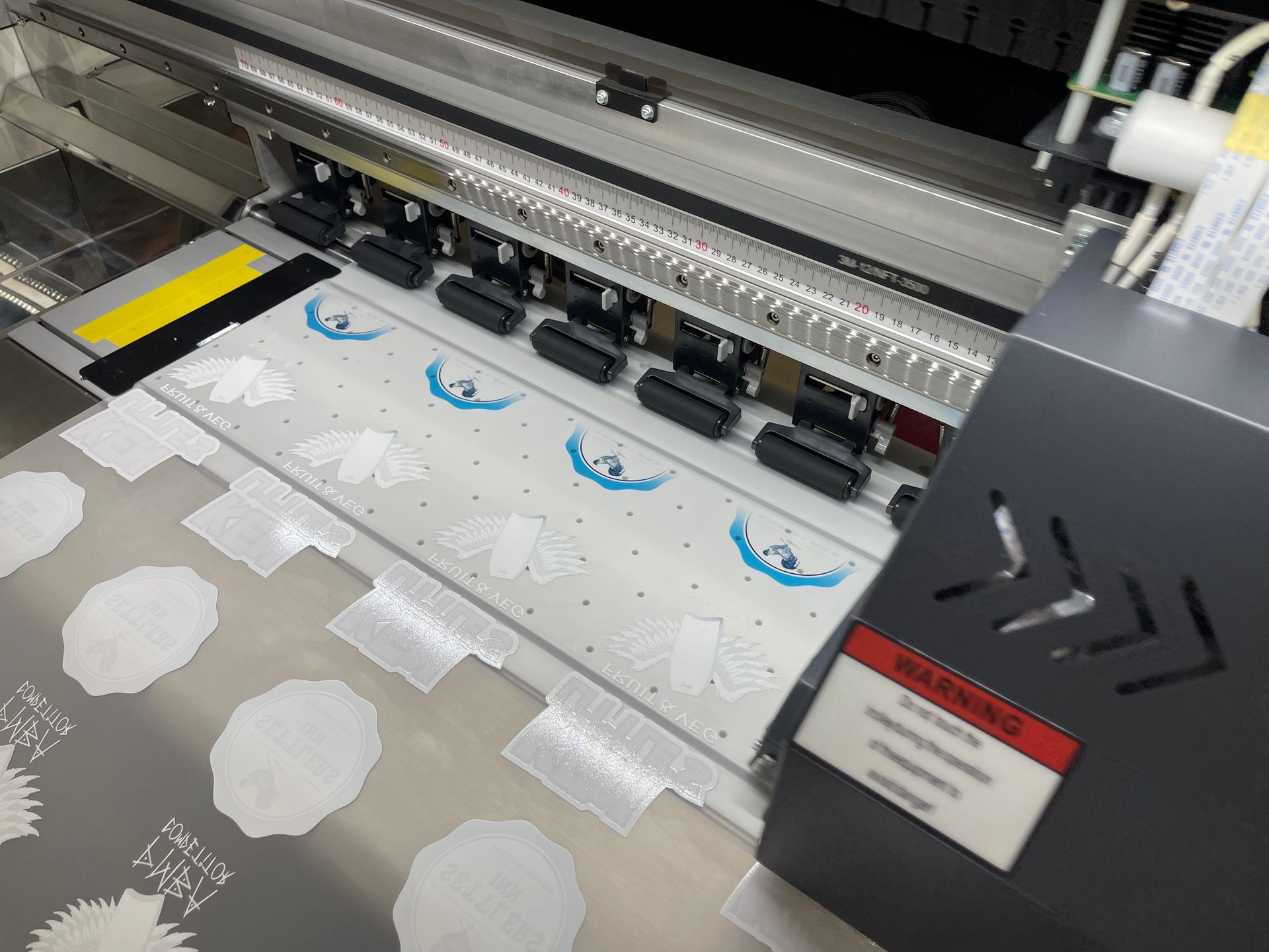 An industrial printer printing blue and white designs onto a sheet of material. — Carbon Copy Digital in Taree, NSW