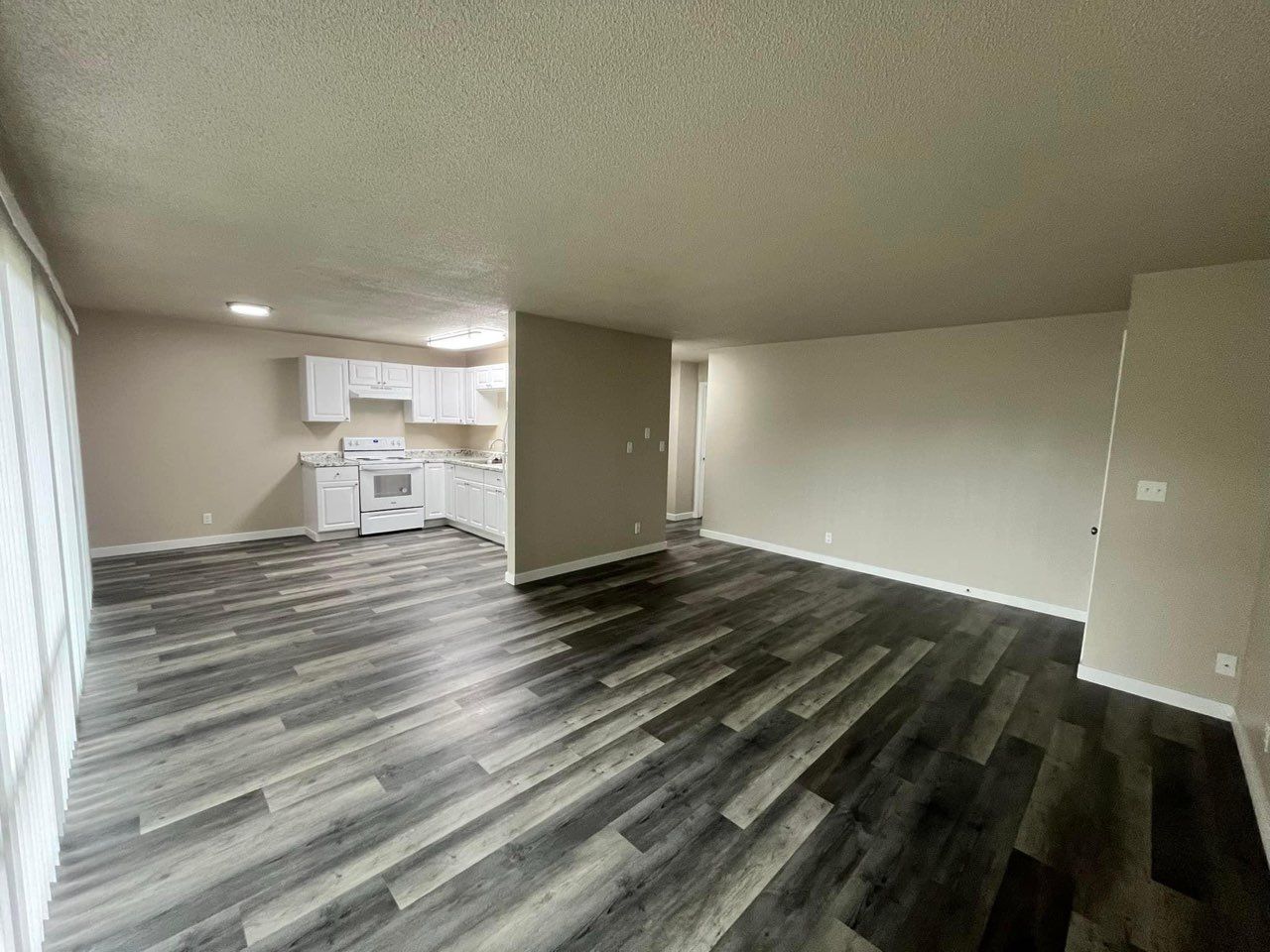 A kitchen with white cabinets , a stove , a refrigerator , and a sink.