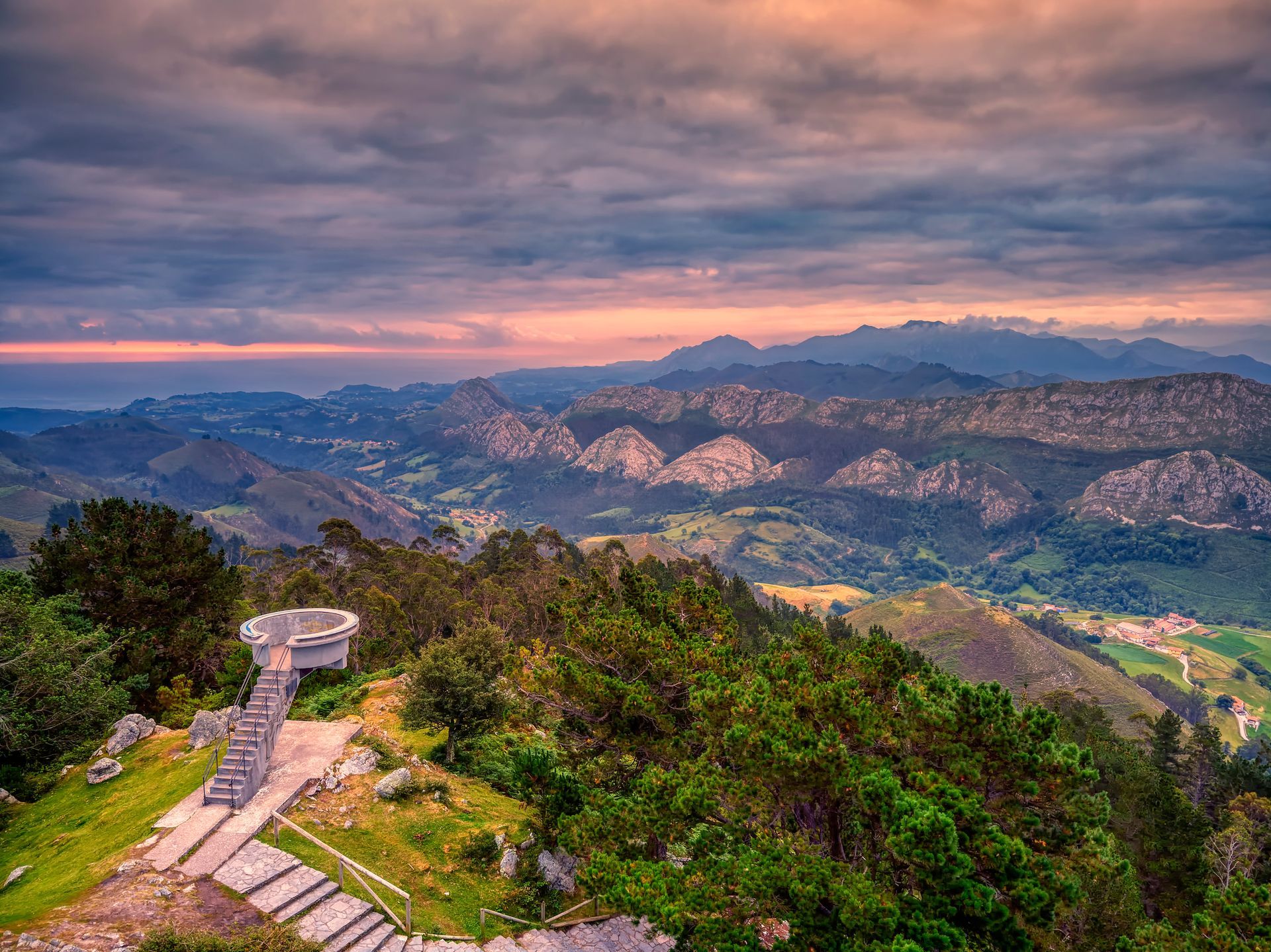 A view of a valley from the top of a mountain at sunset.
