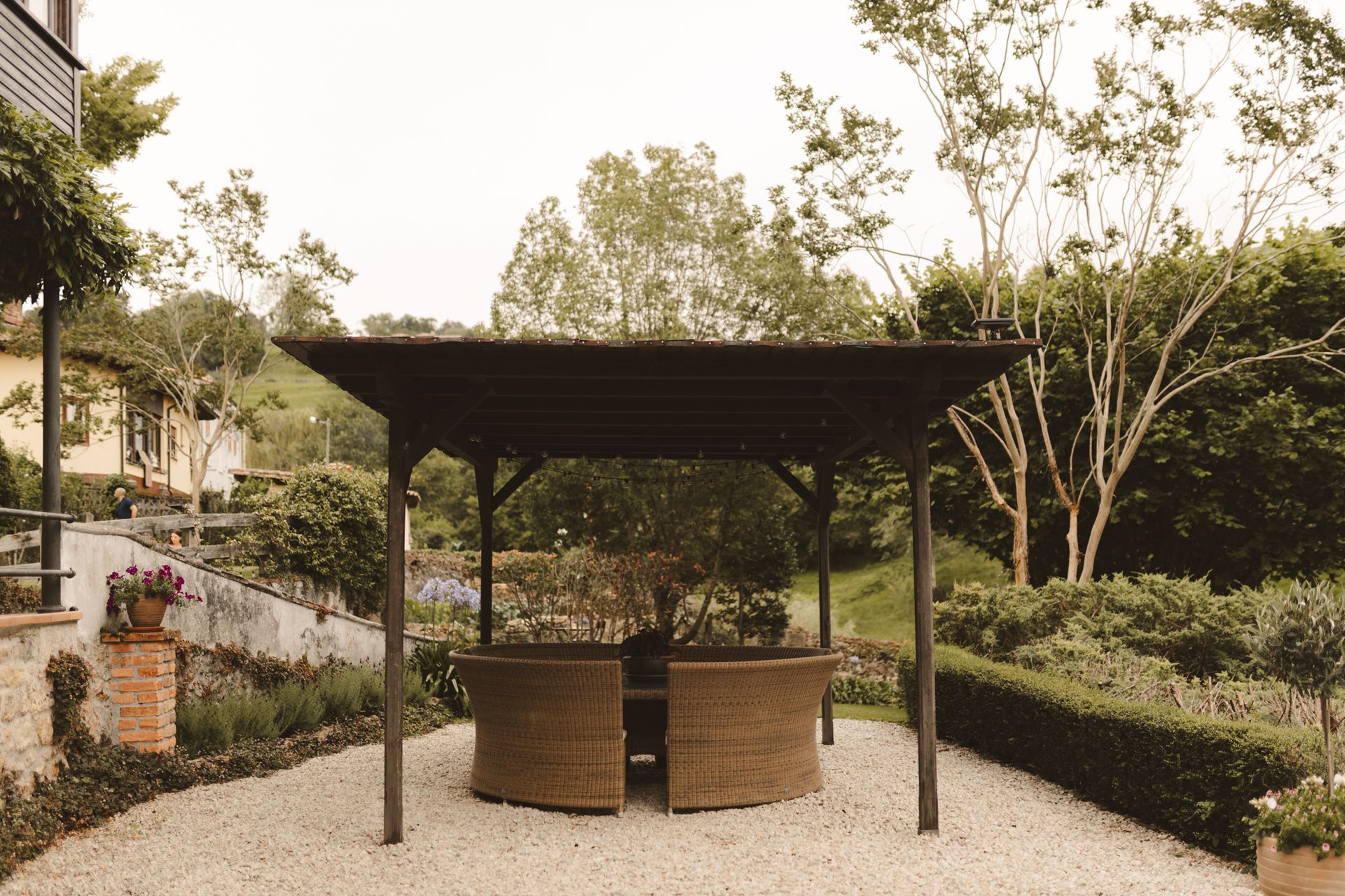 A gazebo with wicker chairs and a table in a garden