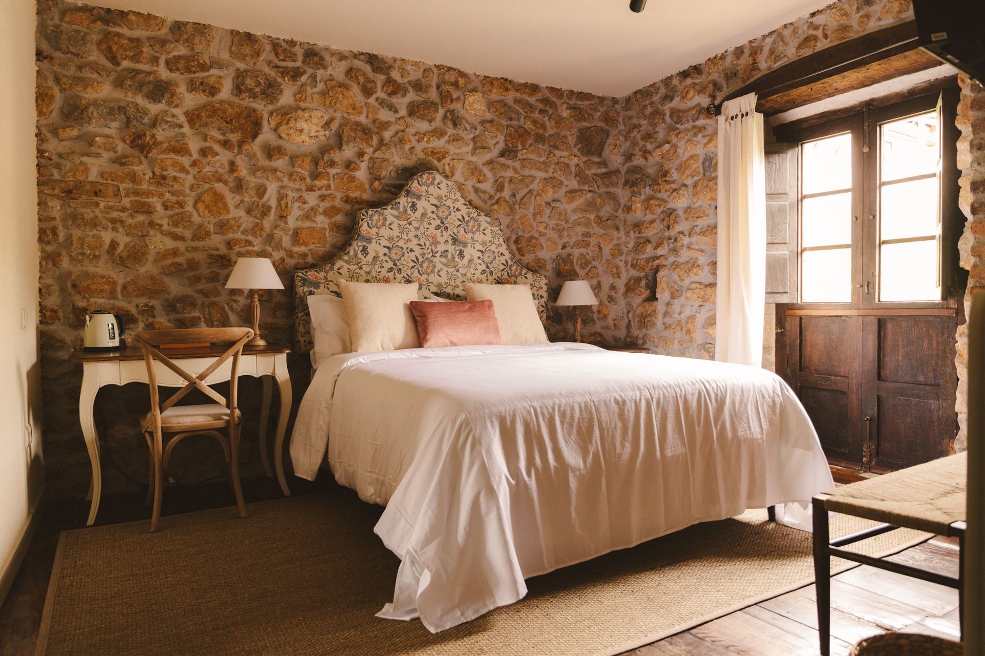A bedroom with a large bed and a stone wall