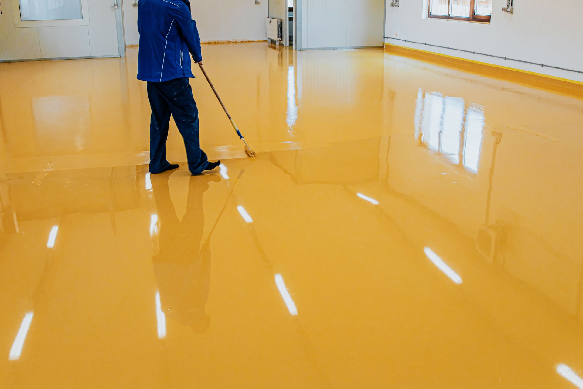 A man is cleaning a yellow epoxy floor with a broom