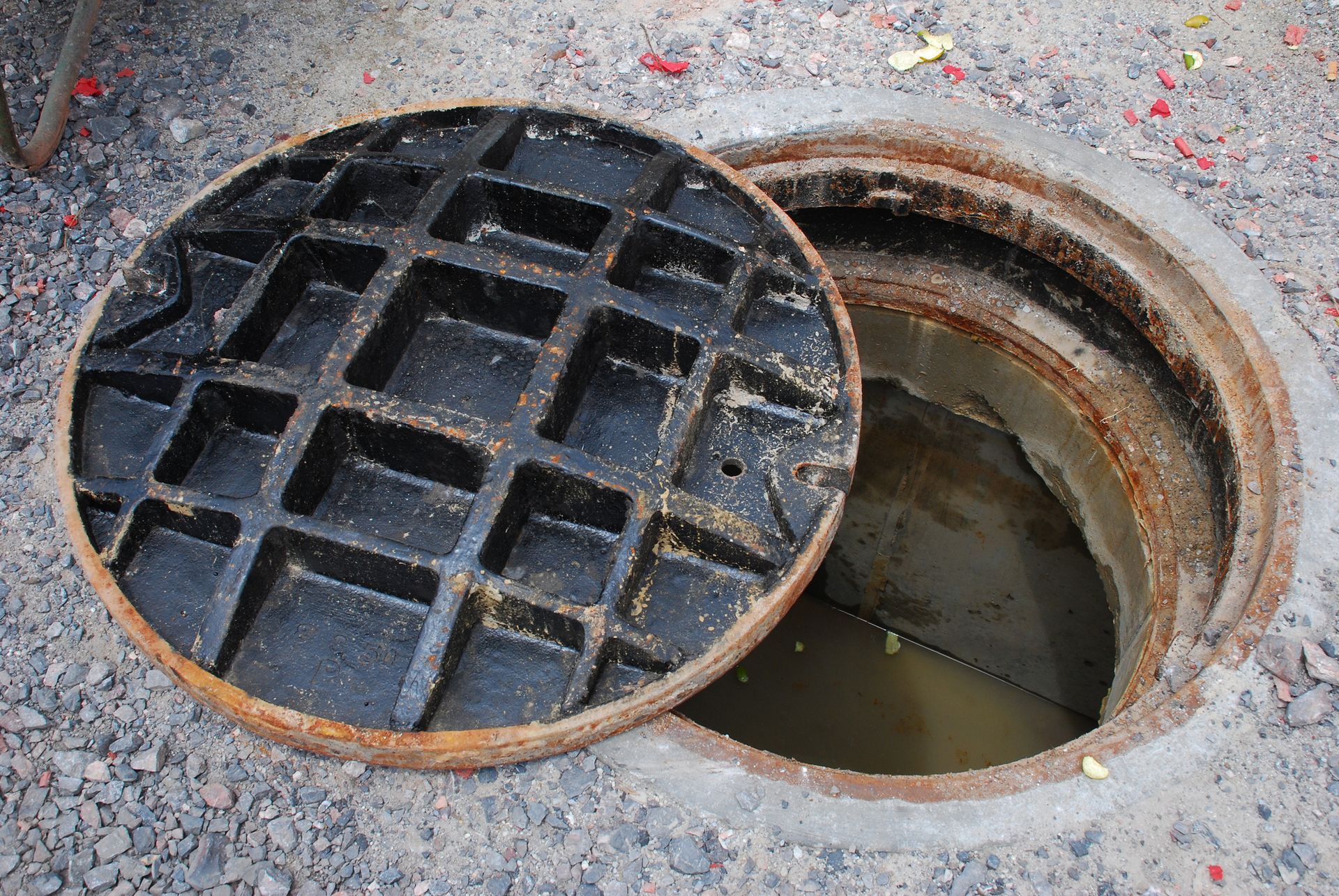 A manhole cover is open on a concrete surface.