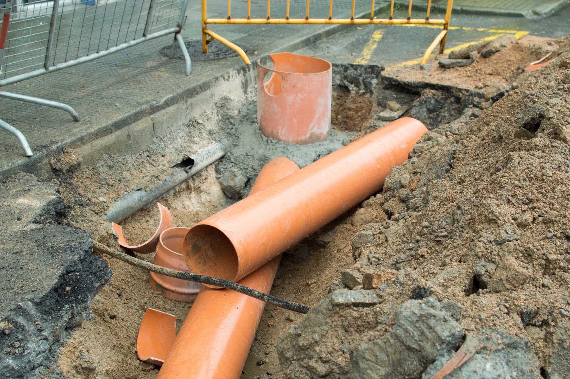 A bunch of pipes are laying in the dirt on the ground.