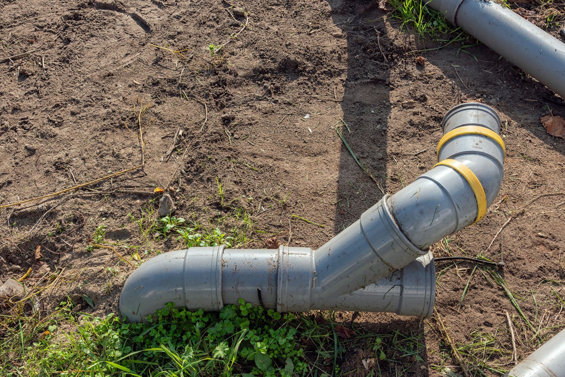 A bunch of plastic pipes are laying on the ground.