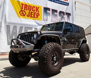 A jeep is parked in front of a truck and jeep fest banner
