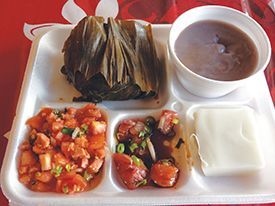 A styrofoam tray filled with food and a bowl of soup.