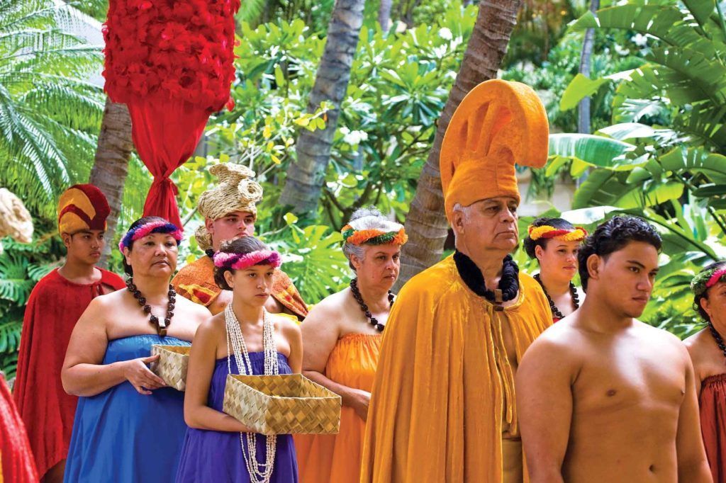 A group of people dressed in traditional hawaiian clothing are standing in a line.