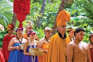 A group of people dressed in traditional hawaiian costumes are standing in a line.