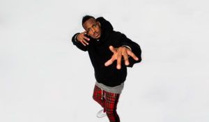 A man in a black hoodie and plaid pants is dancing on a white background.