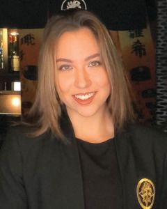 A woman in a black jacket is smiling for the camera