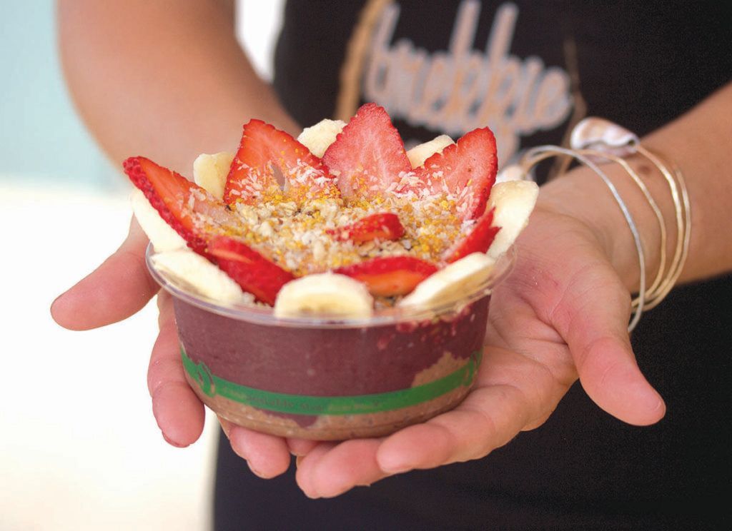 A person is holding a bowl of fruit in their hands