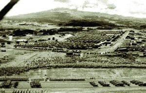 A black and white photo of a military base with a mountain in the background.