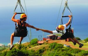 A man and a woman are holding hands while riding a zip line.