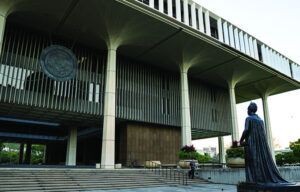 A statue of batman is in front of a large building.