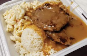 A styrofoam container filled with rice , macaroni and cheese , and meat.