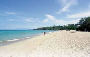 A person is walking on a sandy beach near the ocean.