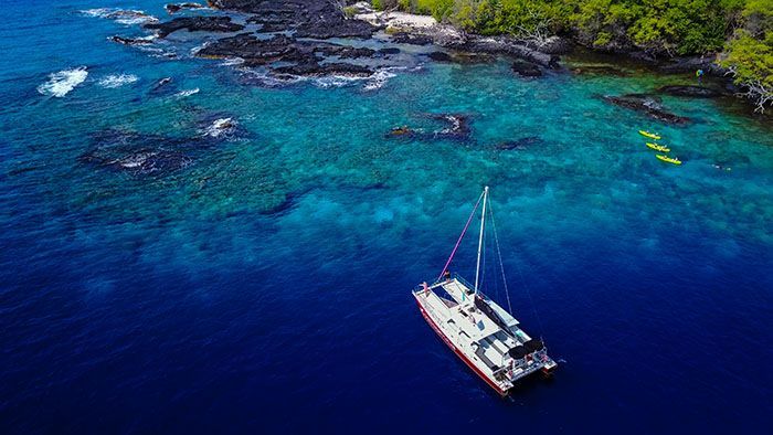 An aerial view of a sailboat in the middle of the ocean.