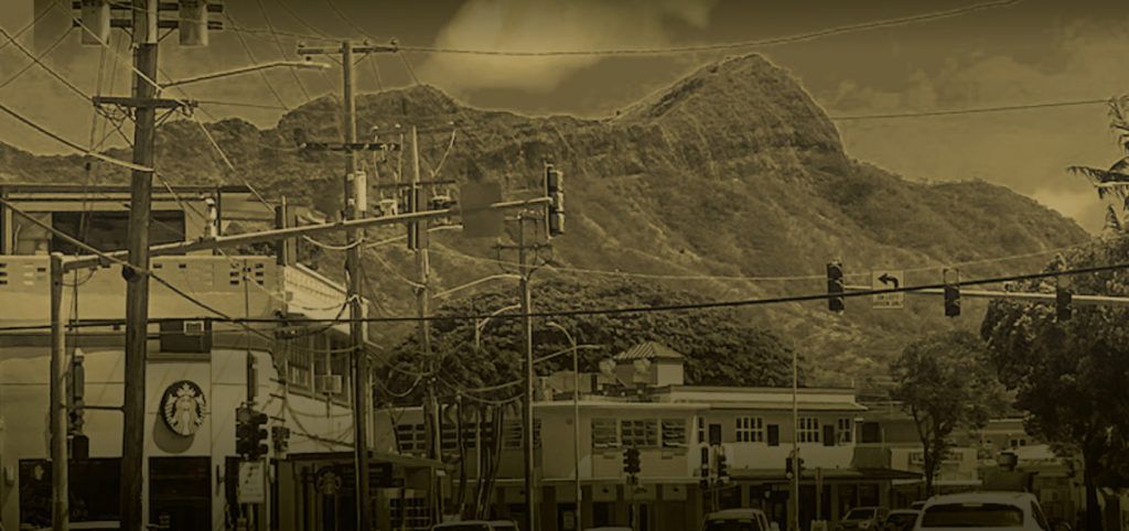 A black and white photo of a city street with mountains in the background.