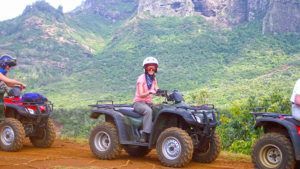 A group of people are riding atvs on a dirt road.
