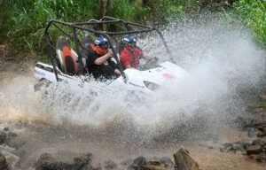 A group of people are riding a atv through a muddy river.