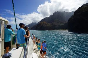 A group of people are standing on a boat in the ocean.