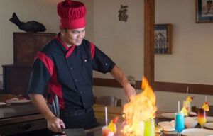 A chef is cooking food on a grill in a restaurant.