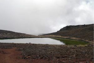 There is a small lake in the middle of a rocky area.