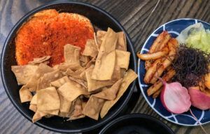 A bowl of food next to a plate of food on a table.